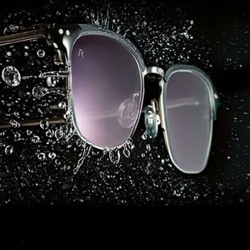 Sonnenbrille mit Wassertropfen auf schwarzem Hintergrund.